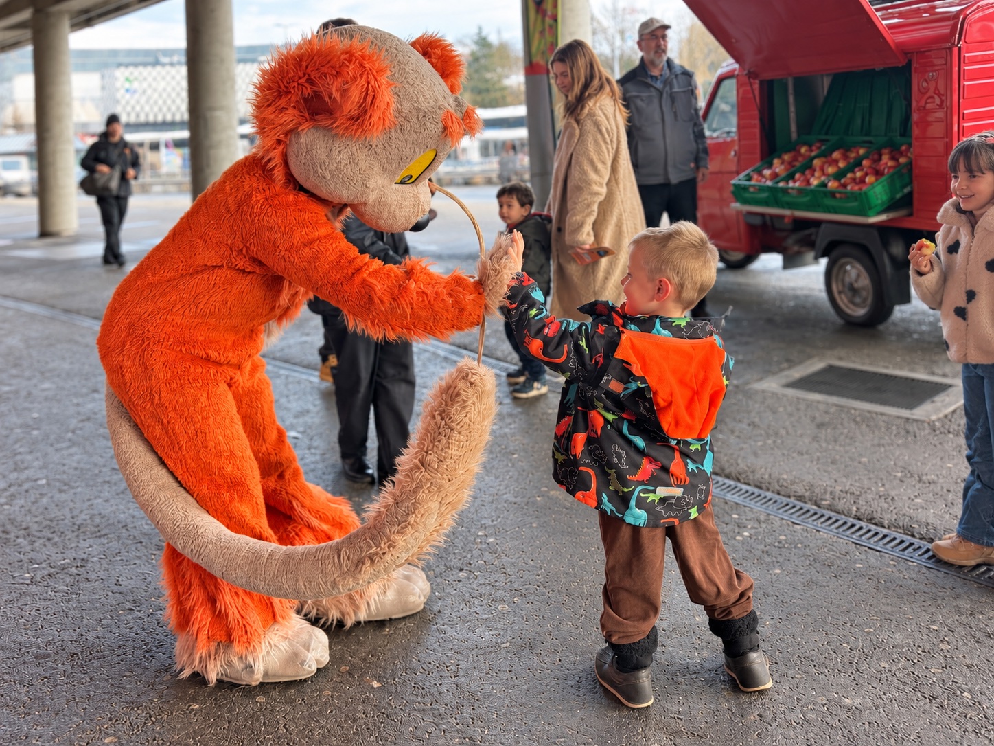 Un enfant échange un geste complice avec une mascotte pendant une animation