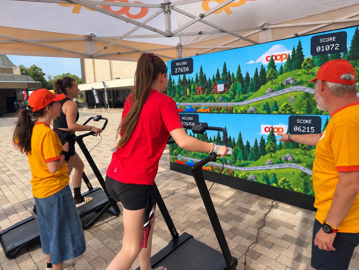 Deux participants sur tapis de course avec les animateurs face au grand écran