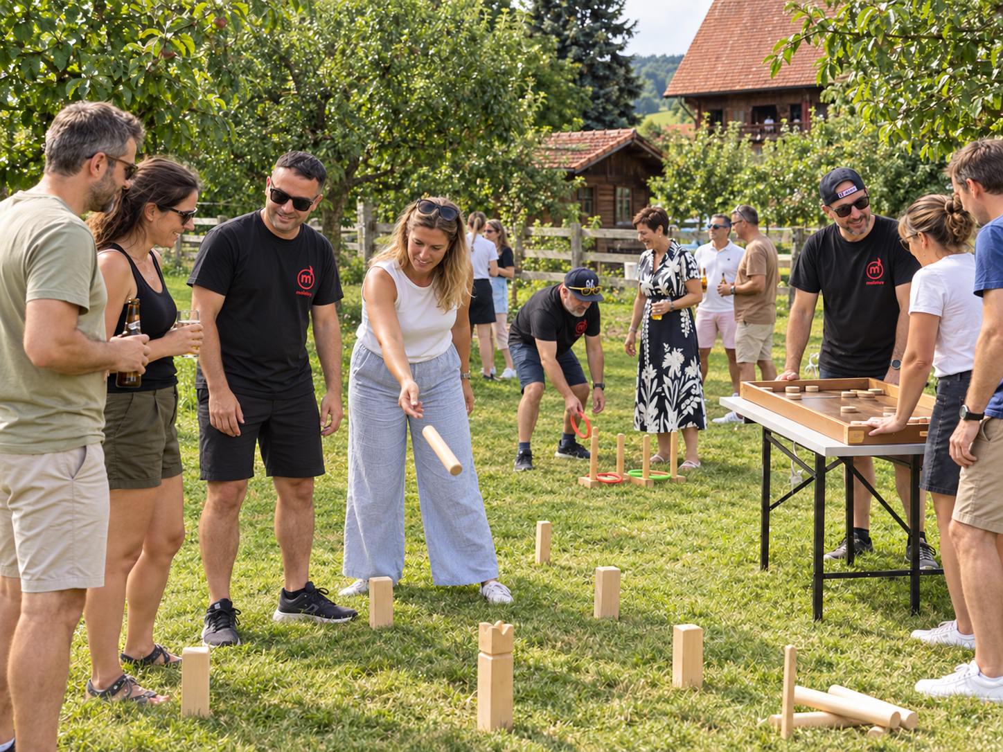 Animateurs Molotov en t-shirts noirs accompagnant des participants autour de jeux en bois dans un verger
